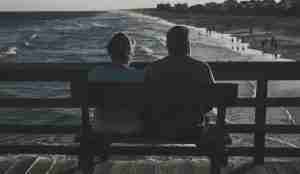 Elderly couple sitting on pier looking at beach
