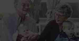 Edlerly couple sitting with two young children in their laps