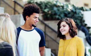 one male teenager and two teenagers talking outside of a house