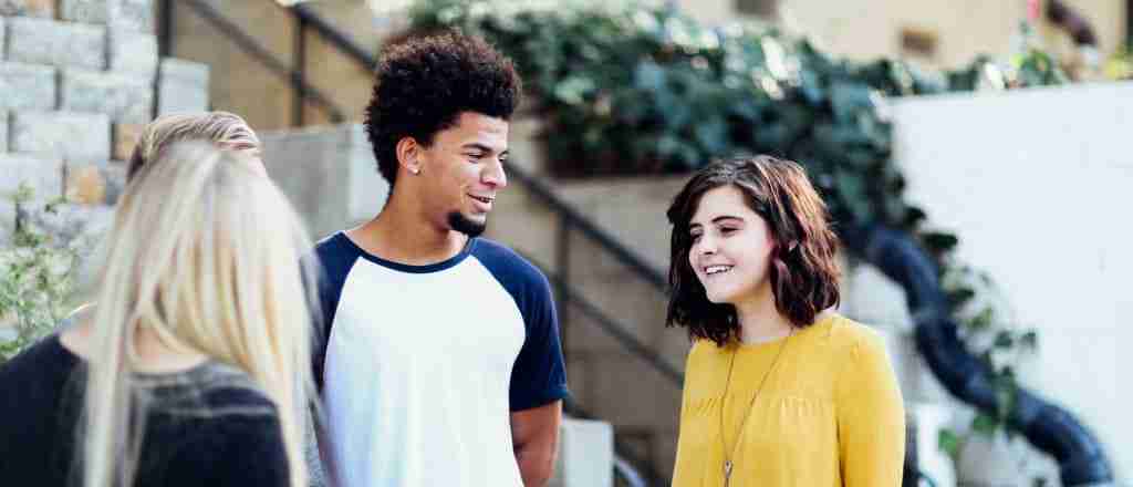 one male teenager and two teenagers talking outside of a house