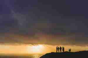 small family looking out towards the sun setting over the ocean