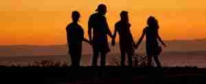 four teenagers holding hands looking out towards the sunset