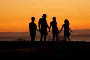 Four teenagers holding hands looking out towards the sunset