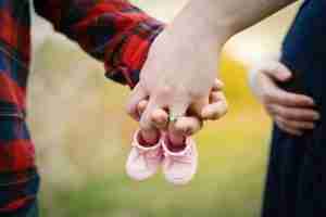 child and mother holding small pink shoes together