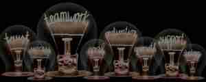 Photo of light bulbs group with shining fibers in a shape of TEAMWORK concept related words isolated on black background