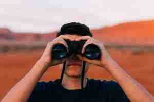 man using binoculars too find innovation insights