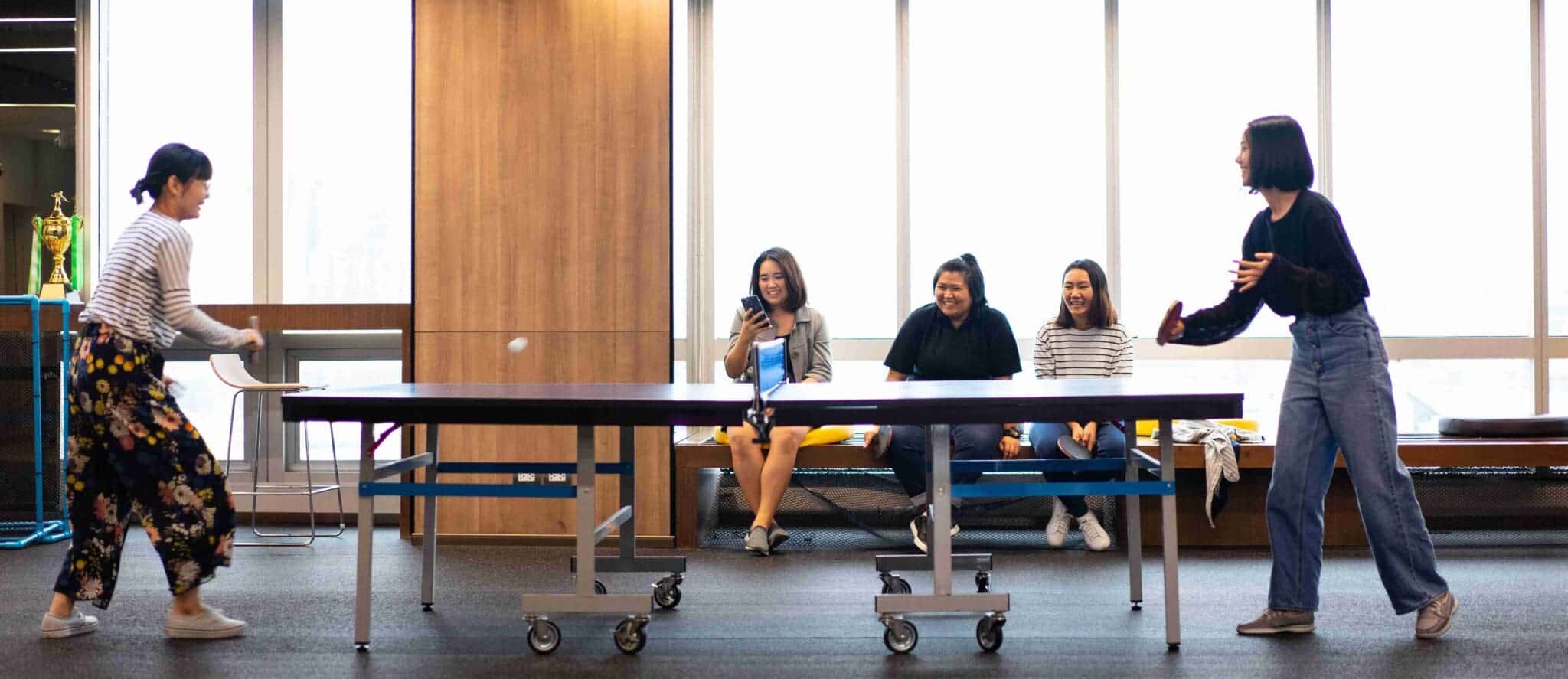 Girls is playing table tennis in free time at the office.