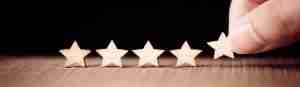 Hand putting wooden five star shape on table representing showing empathy towards customers