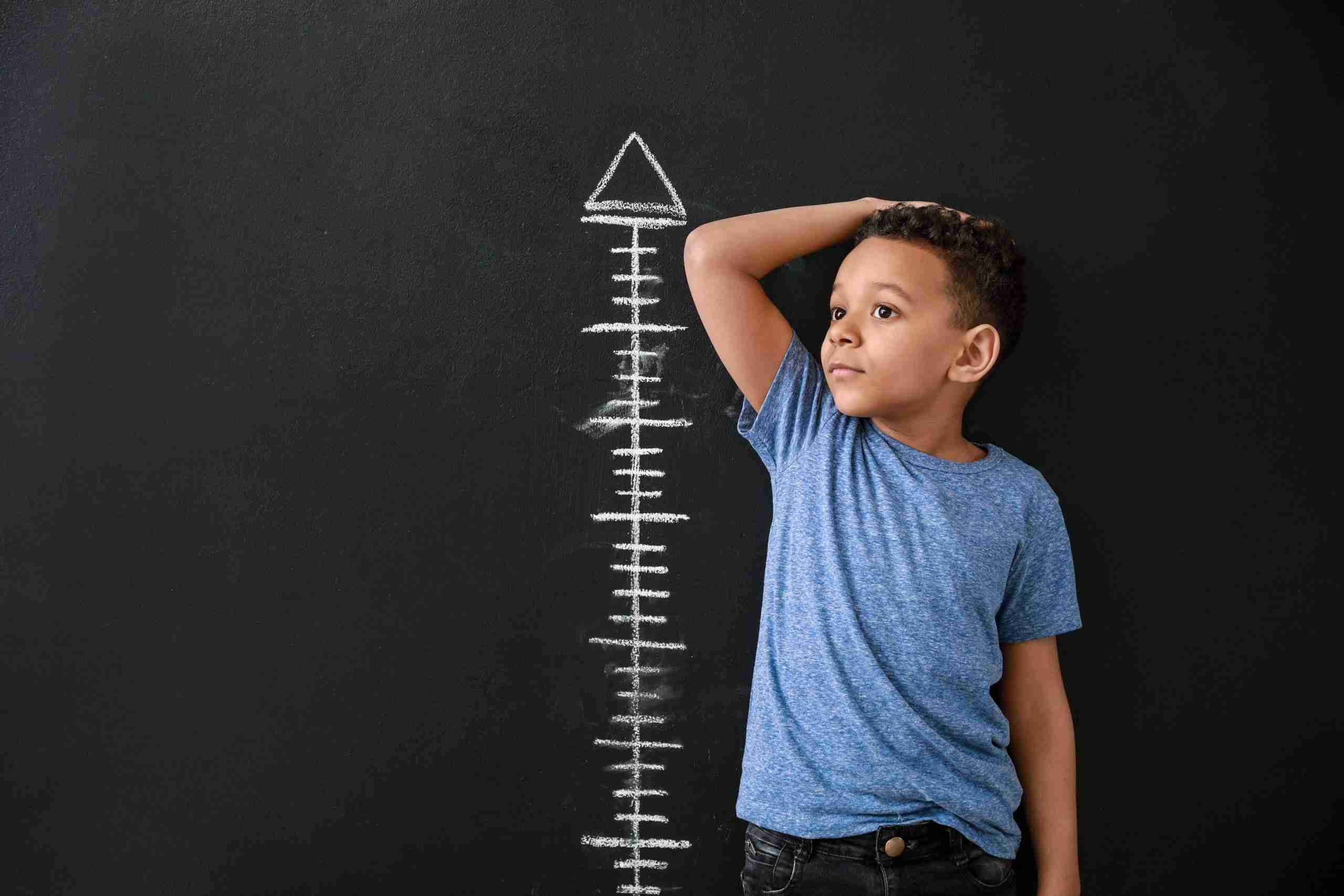 Child next to height chart representing reviewing Business Strategy