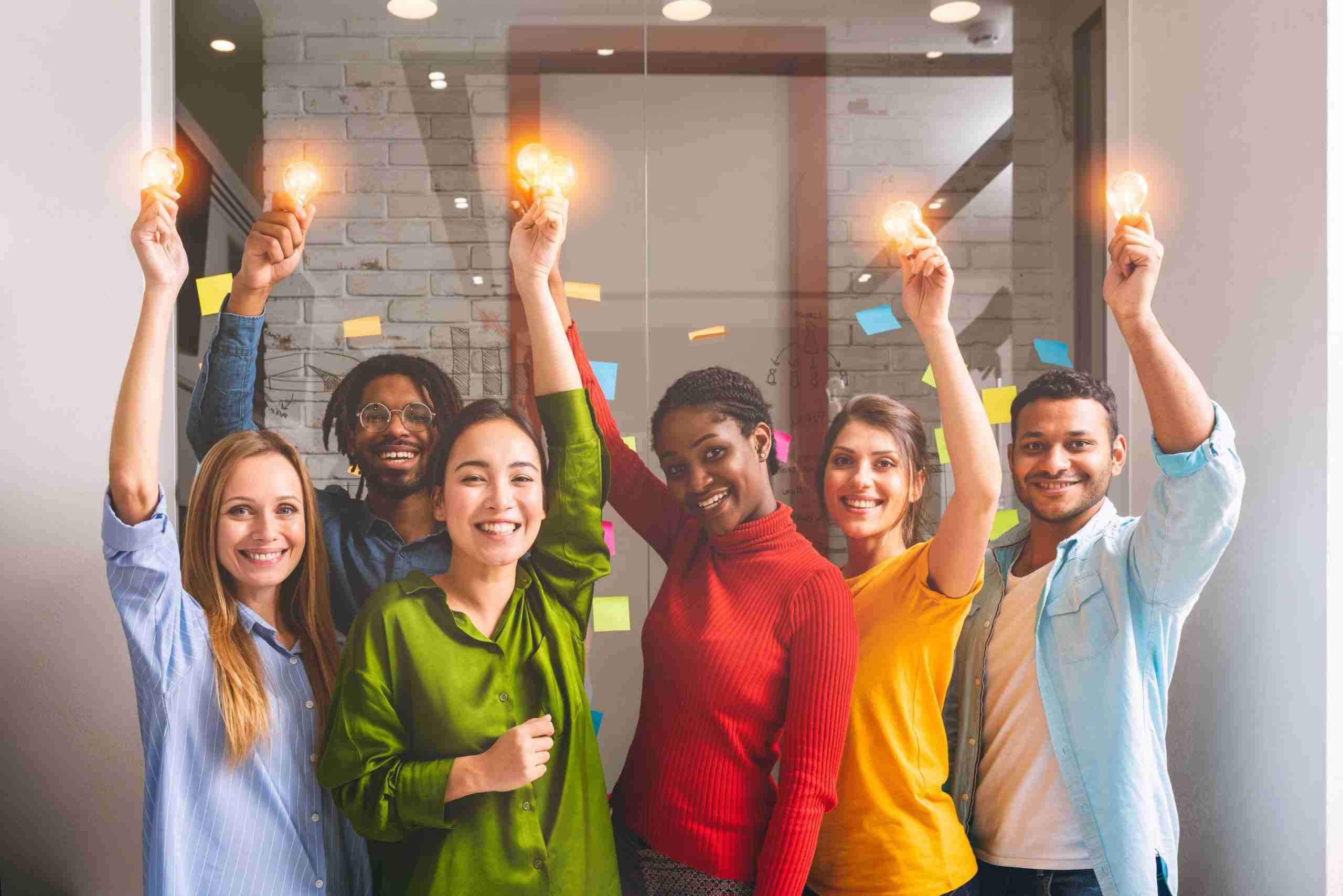 A picture of a team of people holding up lightbulbs, emphasising how a good innovation strategy will place the customer at the centre of the organisation.