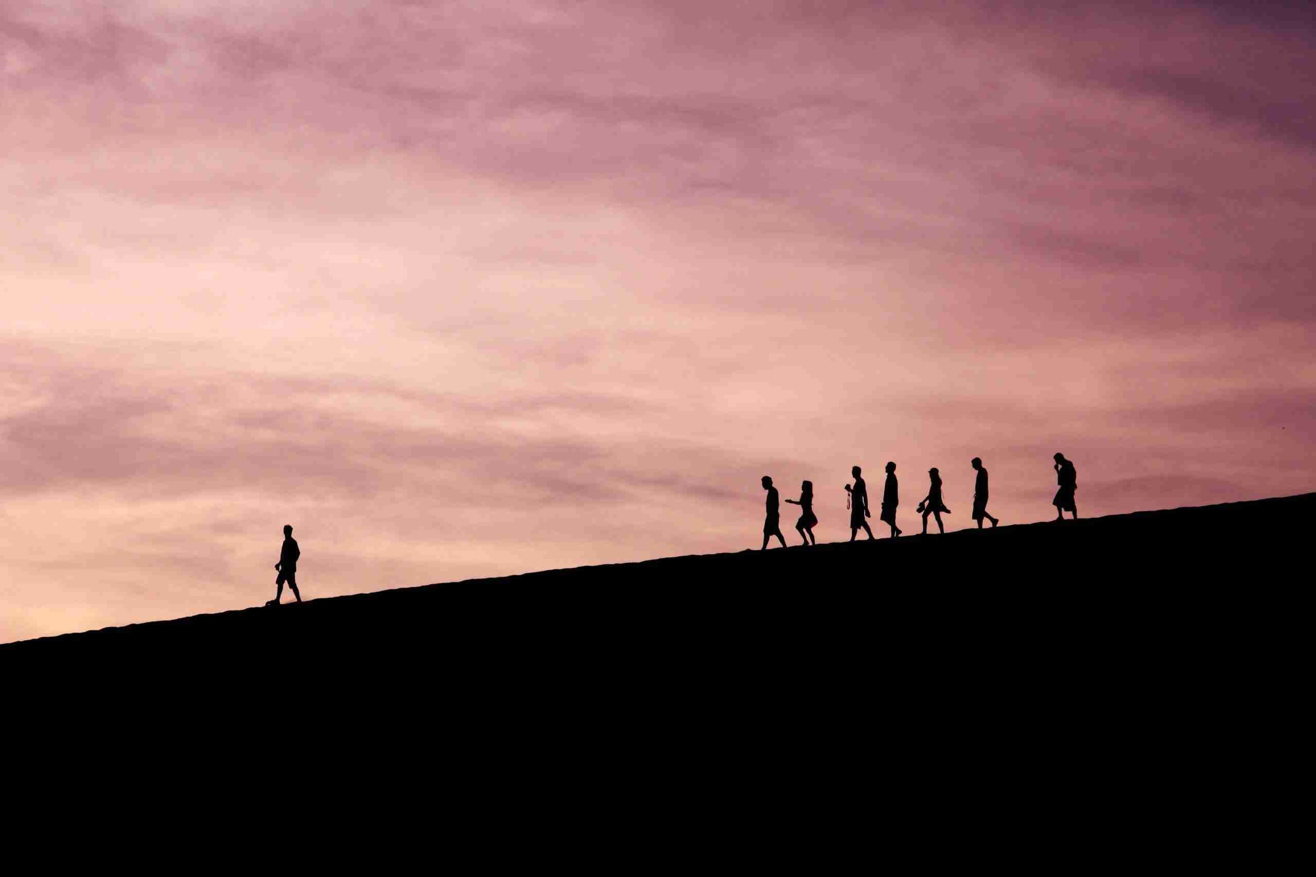 People walking down a hill behind a leader representing innovation strategy