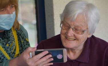 woman in brown button up shirt holding white smartphone