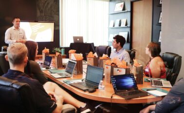 man standing in front of people sitting beside table with laptop computers